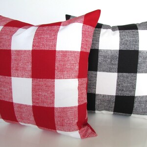 May include: Two decorative throw pillows with a buffalo plaid pattern. One pillow is red and white, and the other is black and white.