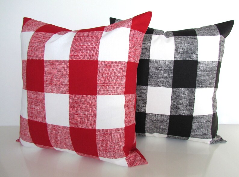 May include: Two decorative throw pillows with a buffalo plaid pattern. One pillow is red and white, and the other is black and white.