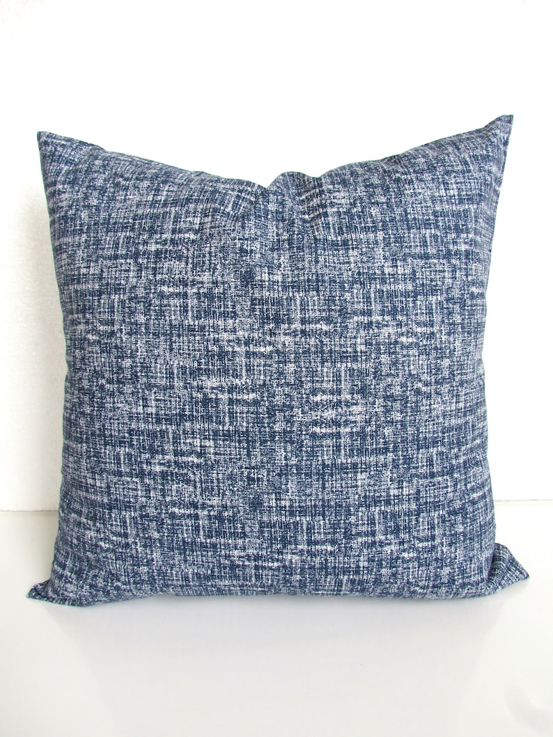 May include: A blue and white patterned throw pillow with a square shape.