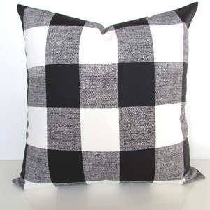 May include: Black and white buffalo check pillow cover. The pillow cover is made of a soft, textured fabric and has a square shape.