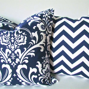 May include: Two decorative throw pillows, one with a navy blue and white damask pattern and the other with a navy blue and white chevron pattern.
