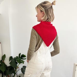 Peut inclure: Un col tricot&eacute; rouge port&eacute; sur un haut &agrave; manches longues vert olive et une salopette blanche. Le col est de forme carr&eacute;e et textur&eacute;e. La salopette a des poches et des d&eacute;tails de couture. La tenue est d&eacute;contract&eacute;e et &eacute;l&eacute;gante.
