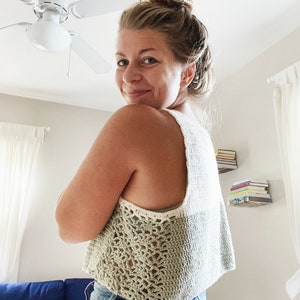 May include: A green and white crochet tank top with a delicate lace trim. The top is cropped and has a relaxed fit.