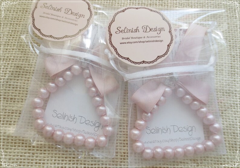 May include: Two packages of pink pearl bracelets, each in a clear bag with a pink ribbon. Each package has a tag with the text "Selinish Design" and the Etsy shop URL.