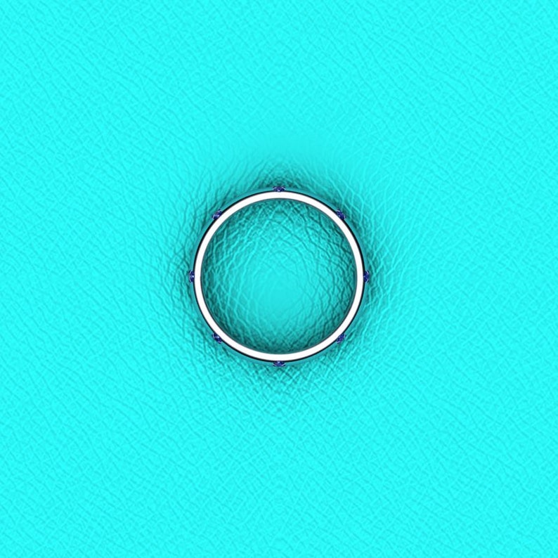 May include: A silver ring with a row of small blue gemstones around the band.