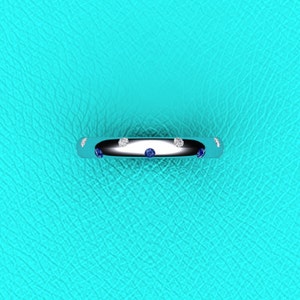 May include: A silver band ring with alternating blue and white gemstones.