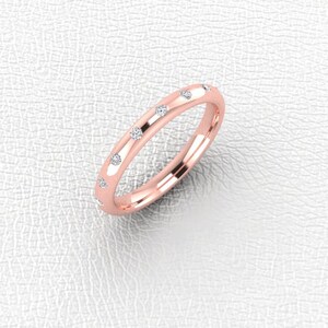 Può includere: Un anello a fascia in oro rosa con piccoli diamanti incastonati attorno alla fascia.