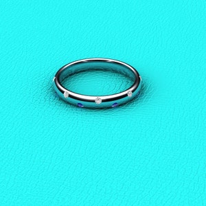 May include: A silver band ring with a row of small, clear gemstones and blue gemstones.
