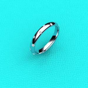 May include: A silver band ring with small diamonds set around the band.