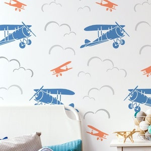 May include: A white wall with a repeating pattern of blue and orange airplanes flying in clouds. The wall is decorated with a stencil.