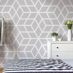 May include: A modern bedroom scene with a geometric patterned wall and a bed with a black and white striped comforter. A white clothing rack holds various shirts and a pair of black heels. A white dresser with a vase of flowers completes the decor.