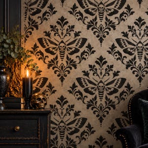 Puede incluir: Papel pintado con un patrón de damasco repetitivo en negro sobre un fondo beige. El diseño incorpora siluetas de polillas con marcas de calavera en el tórax. El estampado es simétrico, con intrincados adornos florales alrededor de cada polilla.