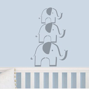 May include: Three gray elephant silhouettes stacked on top of each other on a light blue wall. The elephants are facing right and have their trunks raised.