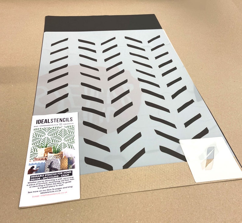May include: A white reusable stencil with a black chevron pattern. The stencil is on a brown surface. The text "IDEALSTENCILS" is visible in the lower left corner of the image.