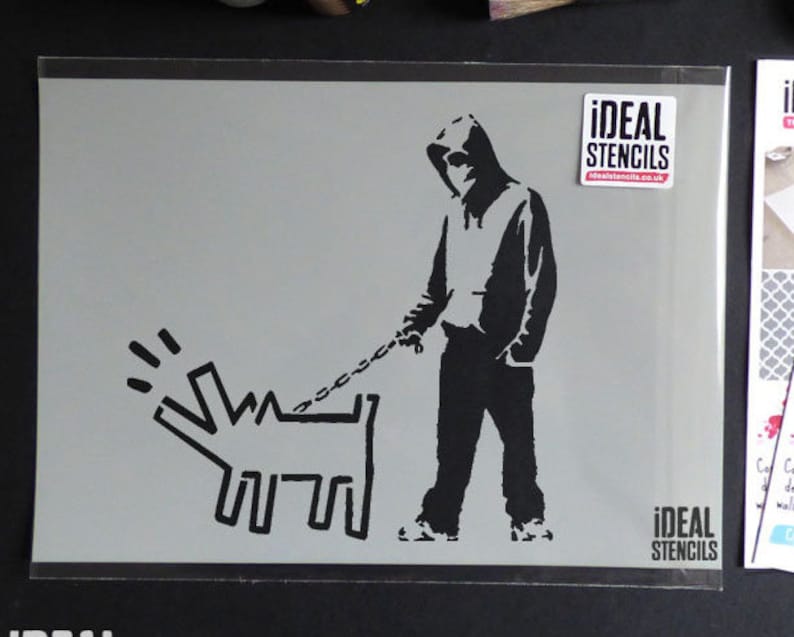 May include: Black and white stencil of a person in a hooded sweatshirt walking a dog on a leash. The stencil is on a gray background and has the text "IDEAL STENCILS" on the bottom right corner.