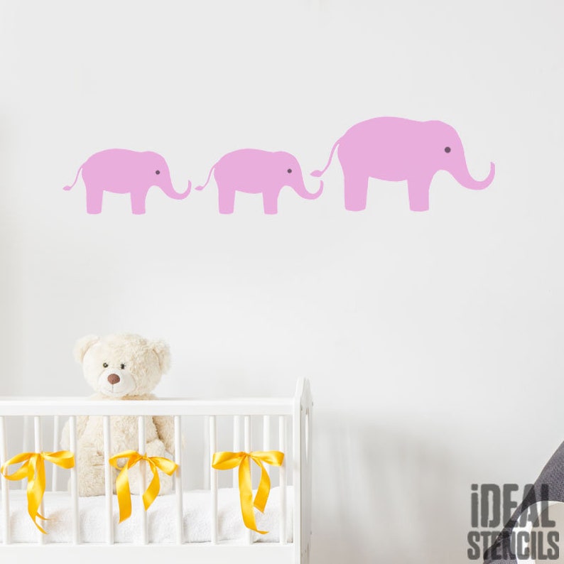 May include: A nursery wall decal featuring three pink elephants in a line, with the largest elephant at the right and the smallest elephant at the left. The elephants are all facing the right side of the image.