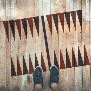 Puede incluir: Un par de zapatos de cuero negro con cordones se encuentran sobre un suelo de madera con un patrón geométrico negro y marrón pintado sobre él.