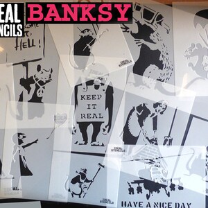 May include: A collection of stencils featuring various designs by Banksy, including a rat holding a peace sign, a rat with a heart balloon, a rat holding a paintbrush, a rat with a parachute, a rat with a sign that says "Keep it real", a rat with a sign that says "Come to Hell", a girl throwing a flower, a woman cleaning a street, and a helicopter with the words "Have a nice day".