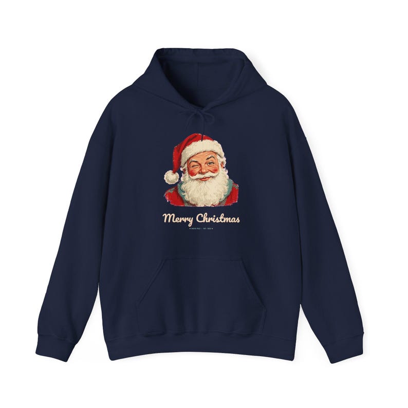 May include: A navy blue hooded sweatshirt featuring a graphic of a winking Santa Claus wearing a red hat with white trim. Below the illustration, the text Merry Christmas is printed in a cream-colored script font on the front of the garment.