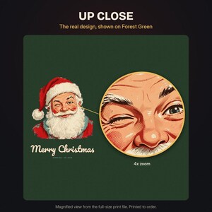 May include: A forest green graphic print featuring a winking Santa Claus in a red hat and white beard with the text Merry Christmas. A circular 4x zoom inset highlights the detailed dot-matrix texture of the Santa face illustration.