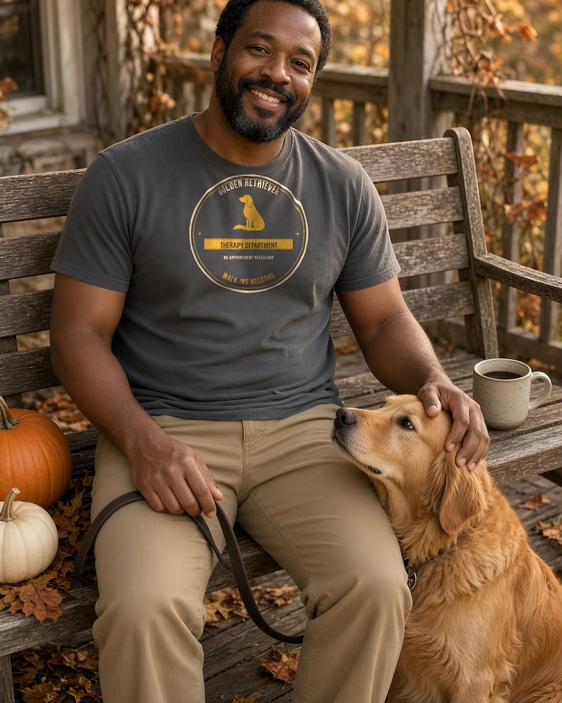 K&ouml;nnte beinhalten: Ein anthrazitfarbenes Kurzarm-T-Shirt mit einer kreisf&ouml;rmigen goldenen Grafik, die die Silhouette eines Hundes und den Text Golden Retriever Therapy Department No Appointment Necessary Walk-ins Welcome zeigt.