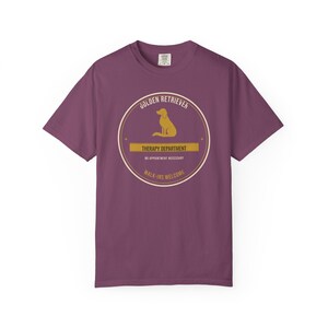 K&ouml;nnte beinhalten: Ein pflaumenfarbenes Kurzarm-T-Shirt mit einer kreisf&ouml;rmigen Grafik, die die Silhouette eines Golden Retrievers zeigt. Der Text lautet: GOLDEN RETRIEVER, THERAPY DEPARTMENT, NO APPOINTMENT NECESSARY und WALK-INS WELCOME in Creme und Gold.