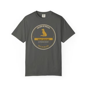 K&ouml;nnte beinhalten: Ein anthrazitfarbenes Kurzarm-T-Shirt mit einer kreisf&ouml;rmigen Grafik, die die Silhouette eines Golden Retrievers zeigt. Der Text lautet: GOLDEN RETRIEVER, THERAPY DEPARTMENT, NO APPOINTMENT NECESSARY und WALK-INS WELCOME in Beige und Wei&szlig;.