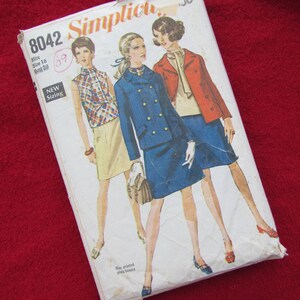 Puede incluir: Un sobre de patrón de costura vintage Simplicity con el número 8042 impreso en el frente. El sobre presenta a tres mujeres con diferentes atuendos, incluyendo un traje de falda azul, una chaqueta roja con una blusa blanca y una blusa a cuadros con una falda beige. El texto "New Sizing" está impreso en el sobre.