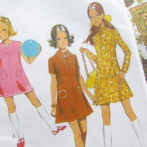 Puede incluir: Un patrón de costura vintage con tres chicas que llevan diferentes estilos de vestidos. La chica de la izquierda lleva un vestido rosa con una cremallera en la parte delantera. La chica del medio lleva un vestido marrón con una cremallera en la parte delantera y un bolsillo a cada lado. La chica de la derecha lleva un vestido amarillo floral con una cremallera en la parte delantera. El patrón es para las tallas 6-14.