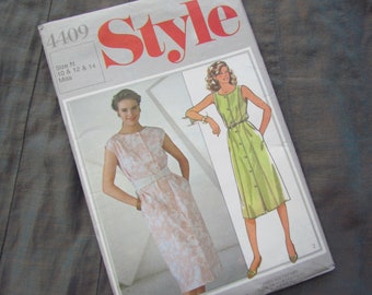 May include: A vintage sewing pattern titled "Style 4409" featuring illustrations of two dresses. One dress is light pink with a white belt, and the other is light green with buttons. The pattern is for sizes 10, 12, and 14.