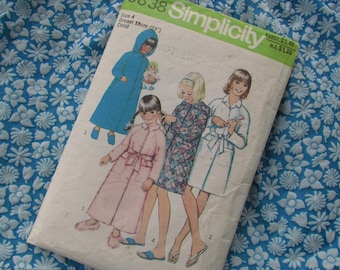 May include: Simplicity sewing pattern for children's robes. The pattern shows four girls wearing different robes, including a blue robe, a pink robe, a floral robe, and a white robe. The pattern is for size 4, with a 23 inch chest.