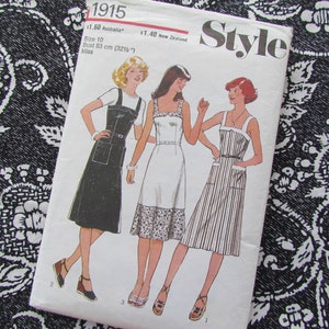 Puede incluir: Patrón de costura vintage "Style 1915" con ilustraciones de tres vestidos. El patrón incluye un vestido negro con peto, un vestido blanco con ribete floral y un vestido a rayas. Talla 10, contorno de busto 83 cm.