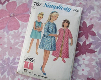May include: Simplicity sewing pattern number 7157 for a child's robe. The pattern is for size 6 and costs 50 cents. The pattern shows three girls wearing different robes. One robe is blue with white flowers, another is pink with a quilted pattern, and the third is a solid blue.
