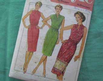 May include: Vintage sewing pattern featuring illustrations of three dresses. The dresses are in shades of red, green, and a floral print. Each dress has a high neckline and a fitted waist. The pattern is on a slightly aged paper.