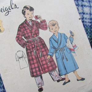 May include: Vintage sewing pattern for boys' robes. The pattern is for sizes 3/4. The pattern shows two boys wearing robes, one in red plaid and one in blue. The pattern is from Weigel's.