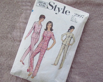 May include: Vintage sewing pattern for a pajama set. The pattern is for a size 12 with a bust of 34 inches and a waist of 25 1/2 inches. The pattern shows three different styles of pajamas, one with a floral print, one with a solid pink color, and one with a plaid pattern.