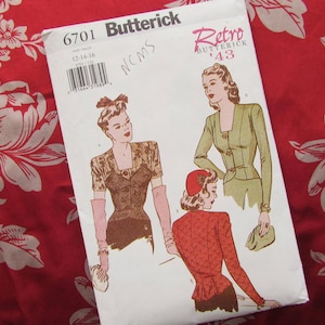 May include: A vintage Butterick sewing pattern, number 6701, featuring retro fashion illustrations. The pattern includes designs for a jacket and other garments. The pattern is set against a red floral fabric background.