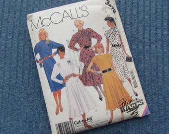 May include: A vintage McCall's sewing pattern envelope featuring illustrations of women's dresses. The cover displays the McCall's logo and the words "Fashion Basics". The pattern includes a variety of dress styles, with a barcode at the bottom.