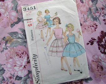 May include: Vintage Simplicity sewing pattern number 3451 for girls' dresses. The pattern includes three different styles: a pink and white striped dress, a blue dress with lace trim, and a blue dress with a white collar. The pattern is for sizes 6-8, bust 24, hip 28. The price is 4/6.