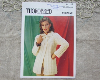 May include: Vintage knitting pattern titled "Thorobred" featuring a woman wearing a cream-colored, ribbed knit cardigan. The pattern is for sizes 80-100 cm. The cover has a red and green background.