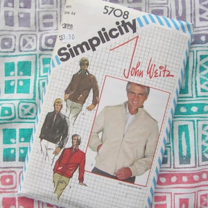 May include: A vintage Simplicity sewing pattern for a jacket designed by John Weitz. The pattern packet shows illustrations of the jacket in brown, black, and red. The background is a colourful fabric with a geometric pattern.