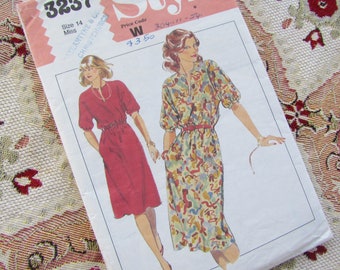 May include: A vintage sewing pattern featuring illustrations of two dresses. One dress is red with short sleeves and a cinched waist. The other dress is patterned with a belt. The pattern includes the size 14 Miss and the text "Style".