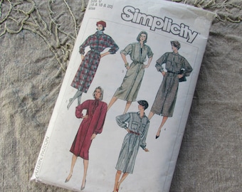 May include: Simplicity sewing pattern envelope featuring illustrations of button-down dresses. The dresses are in various colors and patterns, including plaid and solid hues. The envelope is labeled "Simplicity" in a bold font.