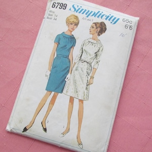 May include: Simplicity sewing pattern number 6799 for two dresses. The pattern is for misses sizes 14 and bust 34. The pattern shows two models wearing the dresses. One dress is blue and the other is white with a floral pattern.
