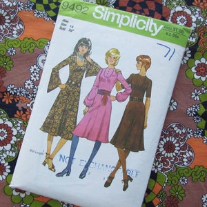 Puede incluir: Un patrón de costura vintage Simplicity para un vestido, con tres mujeres que llevan diferentes estilos de vestidos. El número del patrón es 9492 y la talla es 14, pecho 91 cm. El patrón está sobre un fondo blanco con una tela de estampado floral debajo.