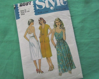 May include: Vintage sewing pattern titled "Style" featuring illustrations of three dresses. The pattern includes a size 12 with a bust measurement of 87 cm. The cover has a blue and white design with the number 2697.