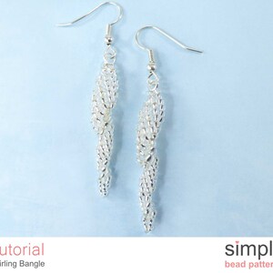 May include: A pair of silver earrings with a swirling design. The earrings are made of small beads and are hanging from silver hooks.