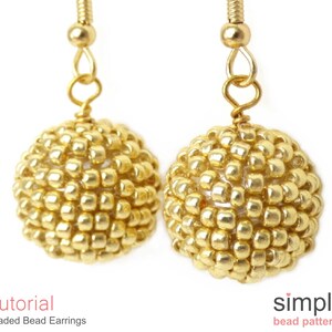May include: A pair of gold beaded earrings with a simple design. The earrings are made with small, round beads that are strung together to create a spherical shape. The earrings are attached to gold hooks.