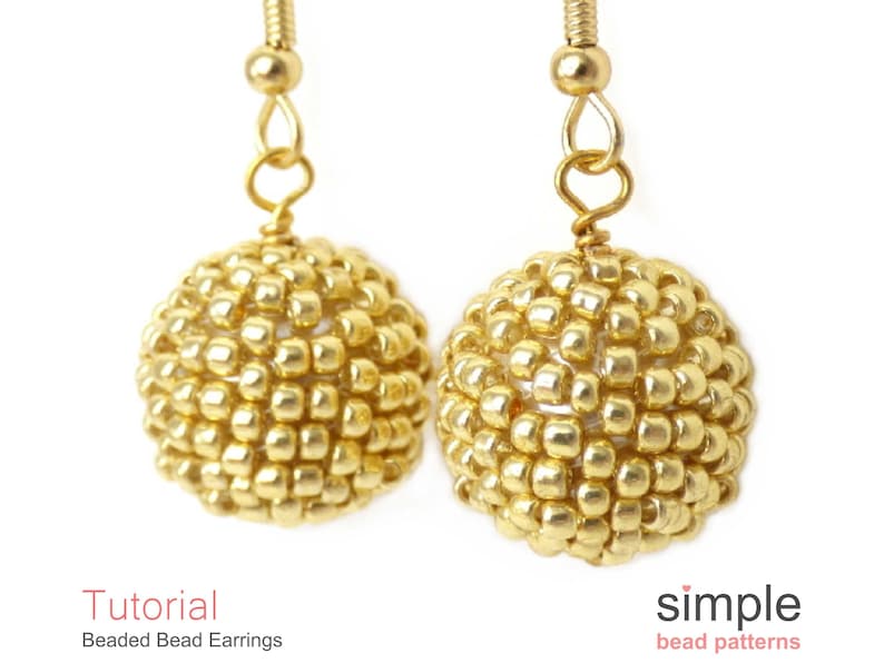 May include: A pair of gold beaded earrings with a simple design. The earrings are made with small, round beads that are strung together to create a spherical shape. The earrings are attached to gold hooks.