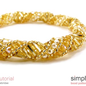 以下が含まれることがあります： ねじれたデザインの金色のビーズブレスレット。ブレスレットは、小さな透明なビーズと大きな金色のビーズで作られています。